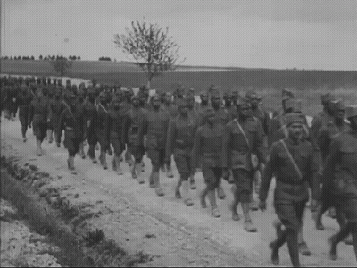 A Group Of Soldiers March Down A Dirt Road GIF