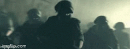 A Group Of Soldiers Wearing Gas Masks Are Walking In The Dark . GIF