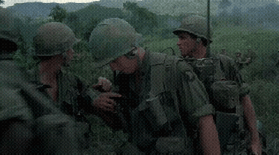 A Group Of Soldiers Wearing Green Uniforms And Helmets Are Standing In A Field GIF