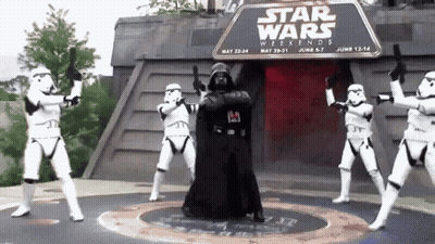 A Group Of Stormtroopers Are Dancing In Front Of A Sign That Says " Star Wars Weekends " GIF