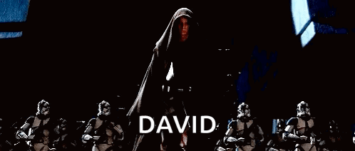 A Group Of Stormtroopers Are Standing In A Dark Room With A Man In A Cape Standing In The Middle . GIF