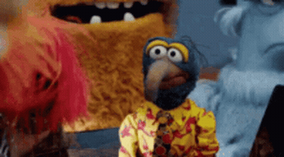 A Group Of Stuffed Animals Are Standing Next To Each Other And One Of Them Is Wearing A Yellow Shirt And Tie . GIF