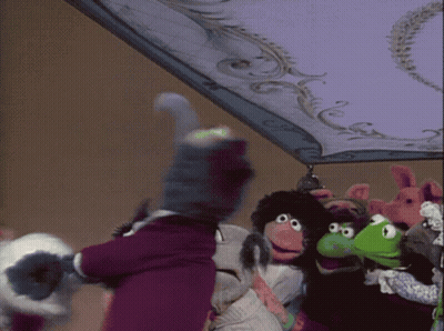 A Group Of Stuffed Animals Are Standing Under A Purple Blanket GIF