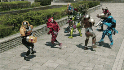 A Group Of Superheros Are Standing On A Sidewalk GIF