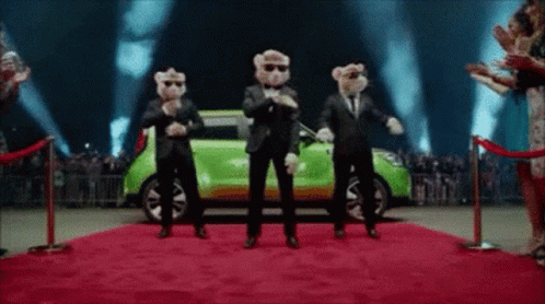 A Group Of Teddy Bears Are Dancing On A Red Carpet In Front Of A Green Car . GIF