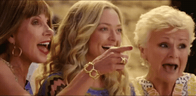 A Group Of Three Women Are Laughing And Pointing At Something . GIF