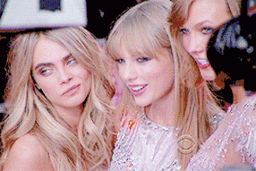 A Group Of Three Women Posing For A Picture With One Of Them Wearing A Cbs Logo GIF