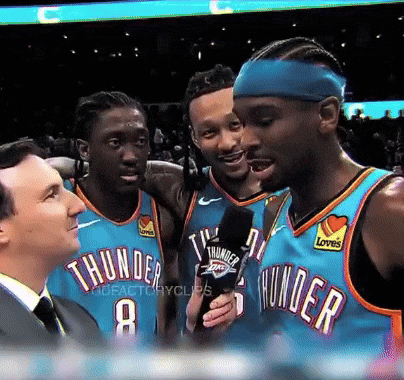 A Group Of Thunder Players Are Talking To A Man In A Suit GIF