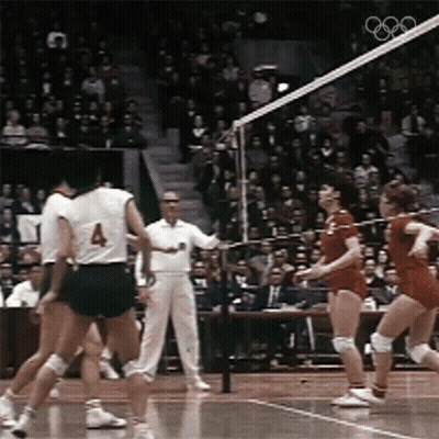 a group of volleyball players are playing a game in front of a crowd