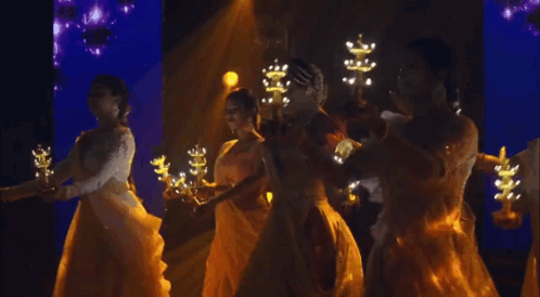 A Group Of Women Are Dancing In A Dark Room Holding Candles . GIF