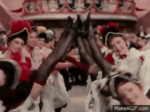 A Group Of Women Are Dancing In Front Of A Crowd In A Can Can . GIF
