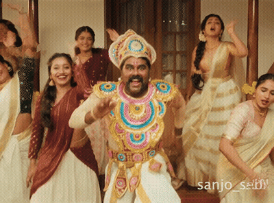 A Group Of Women Are Dancing In Front Of A Man In A Costume With The Name Sanjo Written On The Bottom GIF