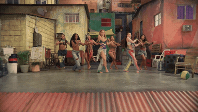 A Group Of Women Are Dancing In Front Of A Red Wall GIF
