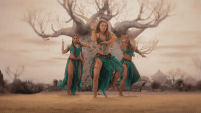 A Group Of Women Are Dancing In Front Of A Tree In The Desert GIF