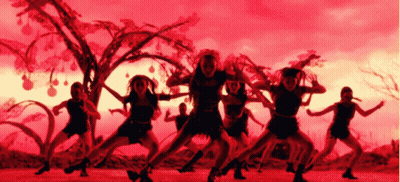 A Group Of Women Are Dancing In Front Of A Tree With A Red Sky In The Background GIF