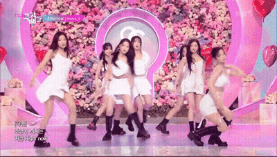 A Group Of Women Are Dancing In Front Of A Wall Of Flowers And Balloons GIF