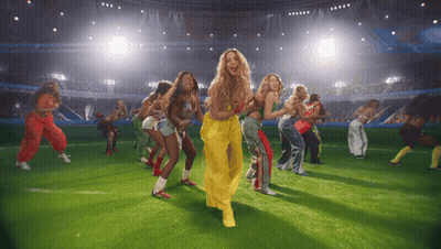 A Group Of Women Are Dancing On A Field In Front Of A Crowd GIF