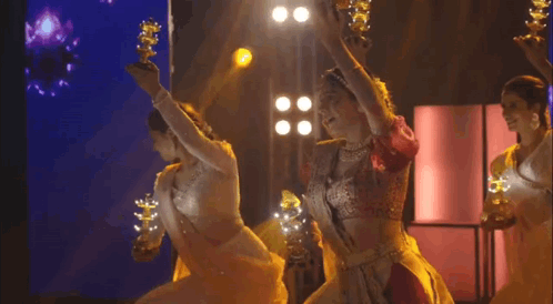 A Group Of Women Are Dancing On A Stage While Holding Candles . GIF
