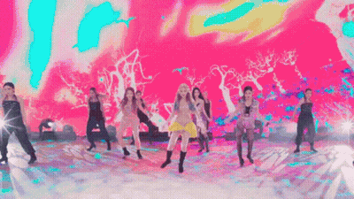 A Group Of Women Are Dancing On A Stage With A Colorful Background . GIF