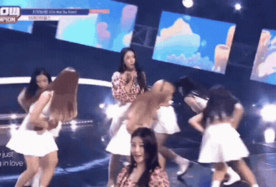 A Group Of Women Are Dancing On A Stage With A Sign That Says Champions GIF