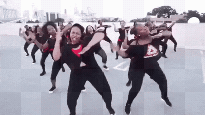 A Group Of Women Are Dancing Together On A Parking Lot . GIF
