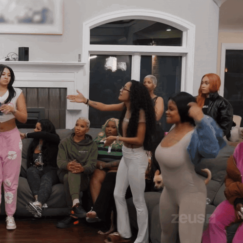 A Group Of Women Are Gathered In A Living Room With The Word Zeus On The Bottom Left GIF