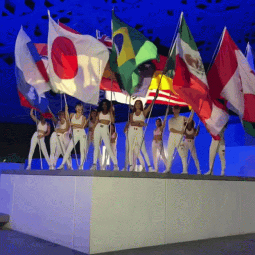 A Group Of Women Are Holding Flags Including One That Has The Letter O On It GIF