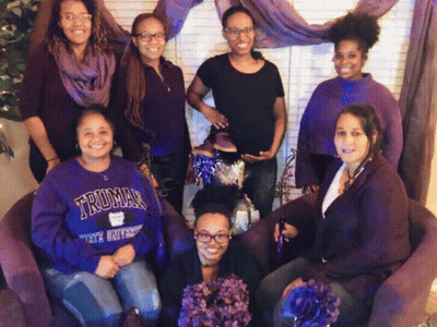 A Group Of Women Are Posing For A Picture And One Of Them Is Wearing A Truman University Sweatshirt GIF