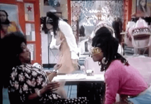 A Group Of Women Are Sitting At A Table Talking To Each Other In A Room . GIF