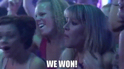 A Group Of Women Are Sitting In A Dark Room With The Words `` We Won '' Written On The Screen . GIF