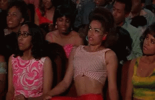 A Group Of Women Are Sitting In A Theatre Watching A Show . GIF