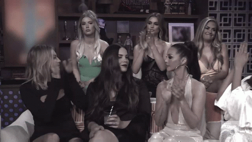 A Group Of Women Are Sitting In Front Of A Wall That Has A Sign That Says ' Storm Chasers ' GIF