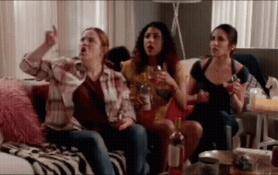 A Group Of Women Are Sitting On A Couch Drinking Wine And Watching Tv . GIF