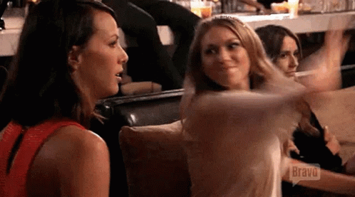 A Group Of Women Are Sitting On A Couch Talking To Each Other . One Of The Women Is Wearing A Red Top . GIF
