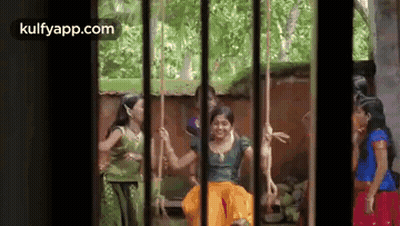 A Group Of Women Are Sitting On Swings In A Cage . GIF