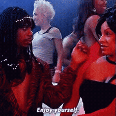 A Group Of Women Are Standing In A Room And One Of Them Says Enjoy Yourself GIF