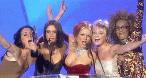 A Group Of Women Are Standing In Front Of A Microphone With Their Arms Outstretched GIF