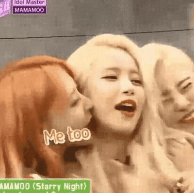 A Group Of Women Are Standing Next To Each Other And One Of Them Is Kissing The Other . GIF