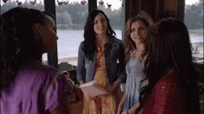 A Group Of Women Are Standing Next To Each Other In Front Of A Window In A Room . GIF