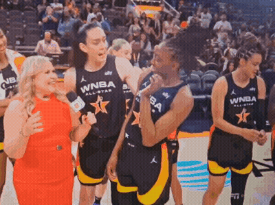 A Group Of Women Are Standing On A Basketball Court And One Of Them Is Wearing A Wnba Jersey . GIF