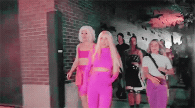 A Group Of Women Are Walking Down A Street . GIF