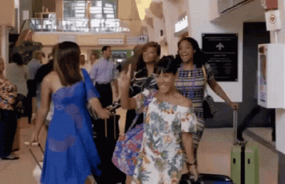 A Group Of Women Are Walking Through An Airport With Luggage And Smiling GIF