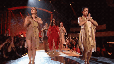 A Group Of Women Dancing On A Stage With Their Hands Together GIF