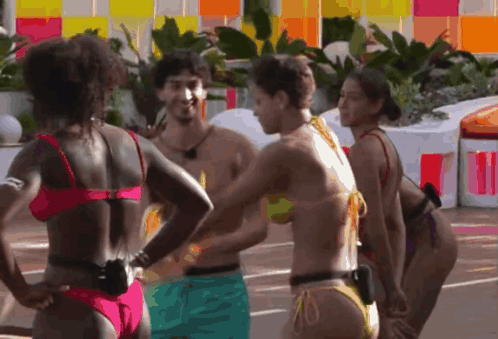 A Group Of Women In Bikinis Are Standing Around A Man GIF