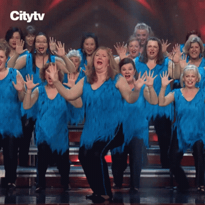A Group Of Women In Blue Dresses Are Dancing On A Stage GIF