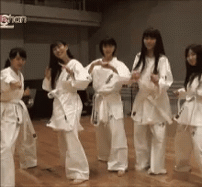 A Group Of Women In Karate Uniforms Are Dancing Together GIF