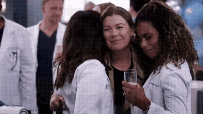 A Group Of Women In Lab Coats Hugging Each Other While Holding A Glass Of Champagne . GIF