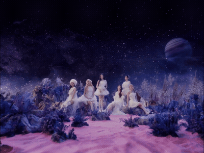 A Group Of Women In White Dresses Are Sitting In A Pink Field GIF