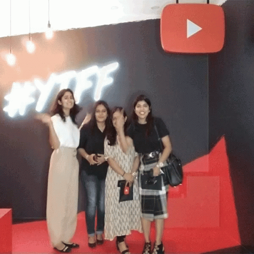 un grupo de mujeres posan frente a un letrero de YouTube GIF