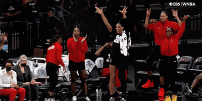 A Group Of Women Standing On A Basketball Court With Their Arms In The Air GIF